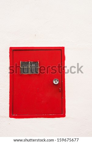 Red door for an electric meter on a whitewashed wall