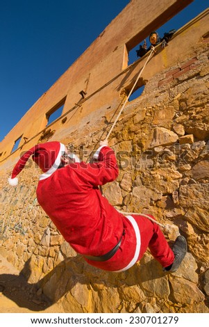 Santa climbing a wall while a scary Halloween monster is waiting for him