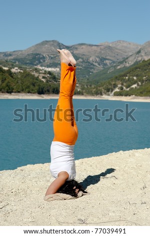 Fit and balanced woman doing a yoga handstand outdoors