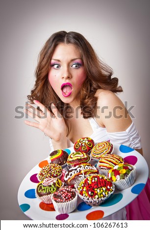 Portrait of young surprised woman eating cakes isolated on white background . Big plate with many cakes