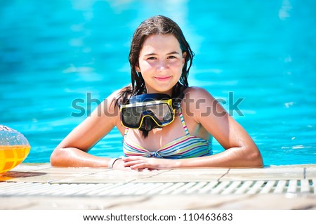 portrait of happy beautiful teen girl at the pool smiling at camera .Teen girl  surrounded by aqua pool water.