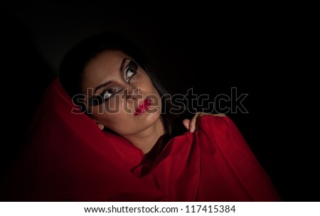 Fashion girl with red scarf and makeup posing on dark background - portrait .Seductive woman isolated on black background with red scarf .Close up portrait