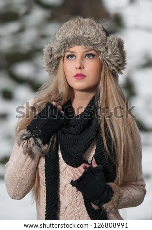 pretty young woman in a winter fashion shoot.Winter wild girl on snow.Winter Girl with beautiful make up, and snow flake, forest background.Portrait of attractive girl