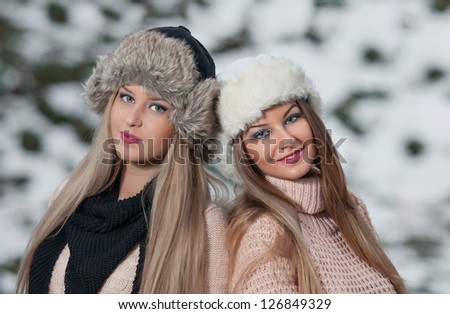 attractive young women in a winter fashion shot.Winter wild girls on snow.Winter Girls with beautiful make up, and snow flake, forest background.Portrait of attractive girls