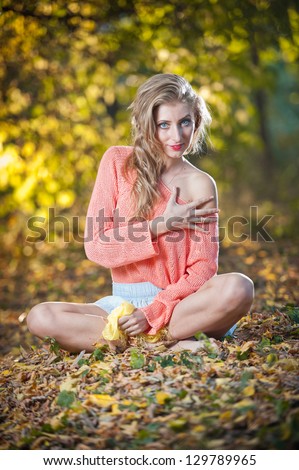 Beautiful elegant woman with long legs in autumn park .Young pretty woman at the autumn park. Beautiful woman spending time in park during autumn season .Young pretty woman at the autumn park