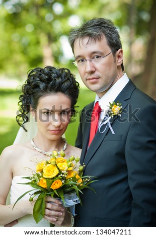 Bride and groom in a park smiling to the camera.Groom and bride embracing in summer forest