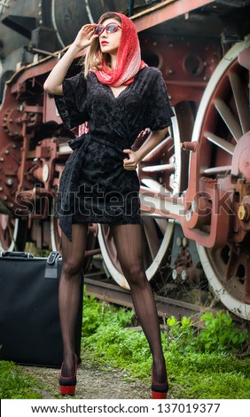 sexy attractive girl waiting for landing on the platform in the vintage train.Vintage woman in twenties style waiting for the train.Retro-styled woman with suitcase on the platform waiting for train