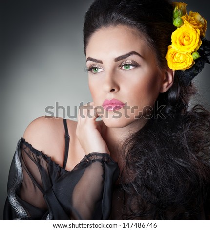 Hairstyle and Make up - beautiful female art portrait with yellow roses.Elegance. Genuine Natural brunette with Flowers. Portrait of a attractive woman with beautiful eyes and flowers in her hair.