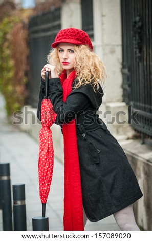 attractive young woman in a winter fashion shot. Beautiful fashionable young girl with red umbrella in the street