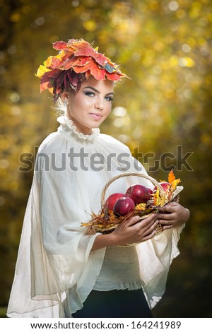 Autumn Woman. Beautiful creative makeup and hair style in outdoor shoot .Beauty Fashion Model Girl with Autumnal Make up and Hair style. Fall. Beautiful fashionable girl holding a basket with apples .