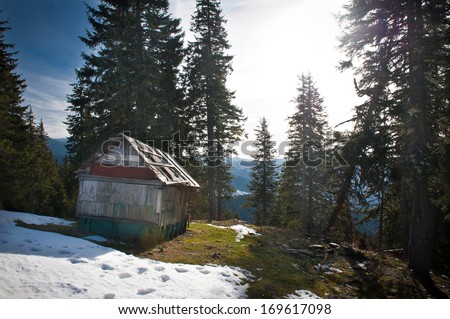 Old wooden cottage in the woods. Majestic sunset in the mountains landscape. Sunset landscape in Carpathian mountains. Dawn in mountains Carpathians, Romania. Mountains covered with snow