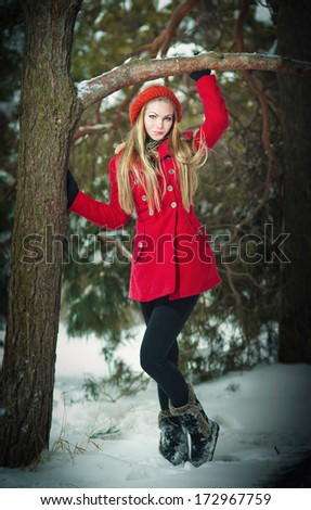 Attractive blonde girl with gloves, red coat and red hat posing winter snow.Beauty woman in the winter scenery.Young woman in wintertime outdoor