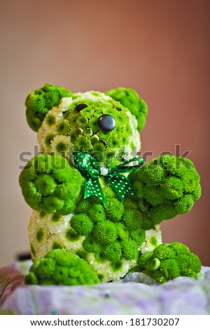 Wedding guest table set for an event. Green bear decoration on restaurant table. Teddy bear made by green flowers to decorate an elegant wedding table.