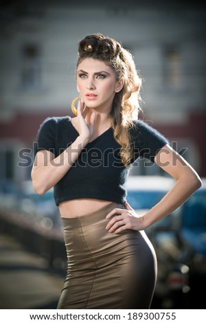 Attractive young woman in a urban fashion shot. Beautiful fashionable young girl with tight-fitting clothes and long legs posing on the street. Elegant blonde female posing in urban scenery