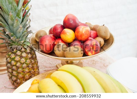 Fruits arrangement. Fresh various fruits elegant decoration. Assortment of exotic fruits. Multicolored fruits. Wedding decoration with fruits on restaurant table, pineapple, bananas, nectarines, kiwi