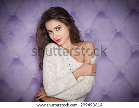 Attractive sexy brunette in white blouse posing provocatively indoor. Portrait of sensual woman in classic boudoir scene against a lilac wall. Beautiful perfect body girl exposing the shoulder