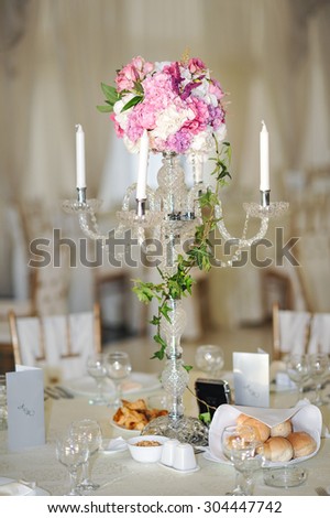 Antique candlestick with wedding bouquet.wedding candlestick with flower decoration before wedding ceremony.Tables set for a wedding reception