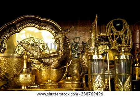 Thai antique gold set for sale at old market. Close up of brass bowl tray and swan. Thailand ancient handicrafts shop. Vintage and retro store for collector and collecting. Decorative art of asia.