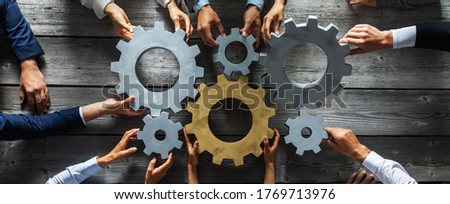 Group of business people joining together silver and golden colored gears on table at workplace top view Photo stock © 