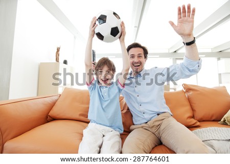 father and son wathcing football inside their house