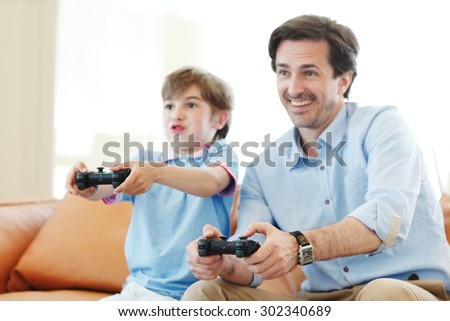 father and son play video game inside their house