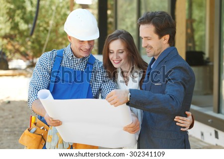 foreman shows house design plans to a young couple