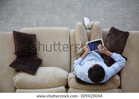man sitting on couch with tablet from top view