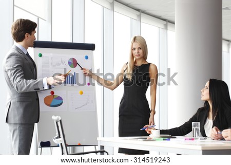 Workers at business meeting looking at presentation of financial reports in modern office