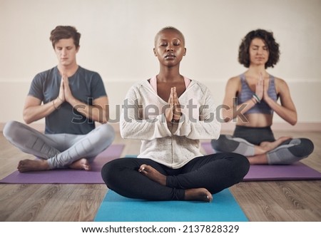 Feeling centred. Full length shot of a diverse group of yogis sitting together and meditating after an indoor yoga session. Foto d'archivio © 