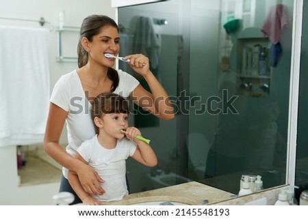 Love is, helping them learn healthy dental habits. Shot of a mother and daughter brushing their teeth together in the bathroom at home. Photo stock © 