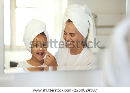 Smiling, joyful and excited little girl in spa with her mother. Mom and daughter self care day, putting on creams and taking care of skin. Parenthood, bonding with child, young female growing up Foto stock © 