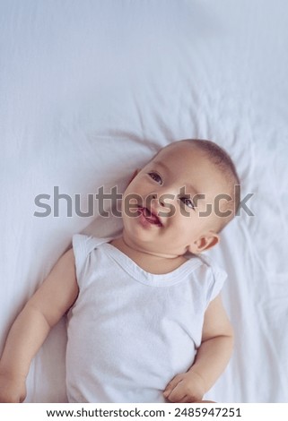 Similar – Image, Stock Photo Curious beautiful baby boy in blue body lying on playing mat, looking in the camera