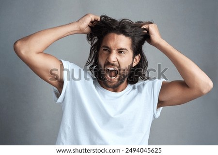 Studio, man and frustrated with pulling of hair for bad news, stress and anxiety on gray background. Angry, male person and expression with screaming for panic attack, mental health and ptsd trauma