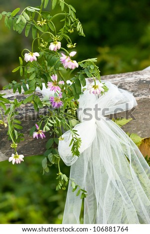 Cut wild flowers tied with lace ribbon on wooden fence post