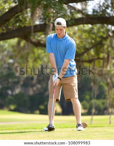 Young male golfer sets up to hit the ball from the tee box