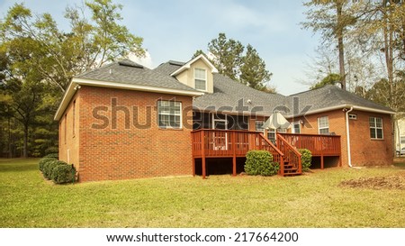 Residential house with backyard deck and large yard.