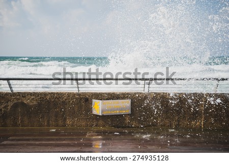 A splash from the Mediterranean Sea at the Port of Tel-Aviv, Israel. The sign reads: \