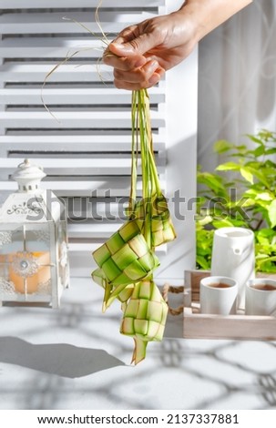 Selective focus of Raw Ketupat, an Indonesian traditional cuisine very popular during Hari Raya Idul Fitri served on white table, window with several cookies and drink with shadow on the background.  Stok fotoğraf © 