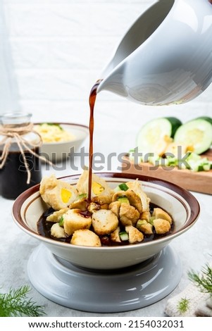 Close up view of Pempek Kapal Selam, traditional food made of Mackerel fish (tenggiri), originated from Palembang, South Sumatera with the brown sauce (cuko) poured from white bowl and some condiments Stok fotoğraf © 
