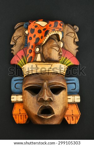 Indian Mayan Aztec wooden carved painted mask with roaring jaguar and human faces isolated on black paper background