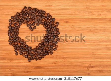Heart shaped coffee beans round frame of Roasted Arabica coffee espresso beans over wooden bamboo board background