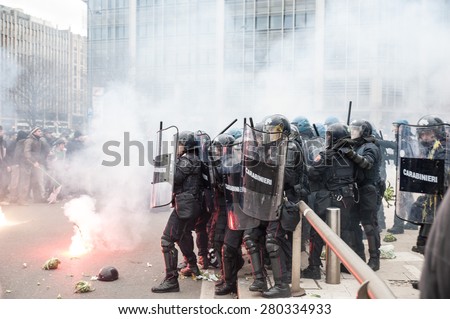 Milan, december 12, 2014 - Riot police in defense mode hold back as students hurl smoke bombs at them at the end of the march in solidarity with the general strike called by Unions in Rome and Turin.
