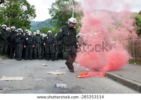 GARMISCH-PARTENKIRCHEN, GERMANY - JUNE 06: Police officer throws away a smoking bomb launched by protesters anti-G7 during the demonstration held the day before the G7 Summit.
