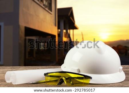 file of safety helmet and architect plant on wood table with  construction