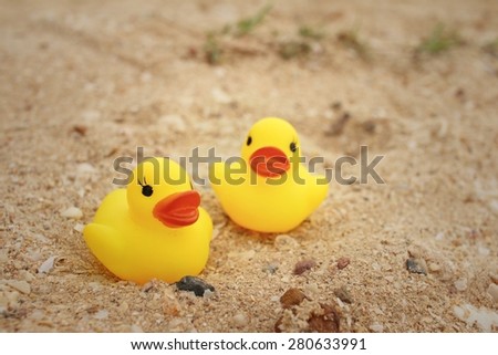 Yellow rubber duck on background of sand.