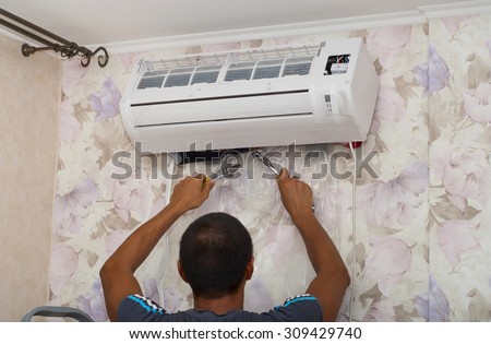 man installs indoor unit of the air conditioner