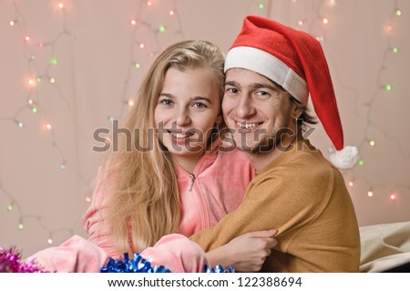young happy couple on bad in new year decorations, garland is behind them
