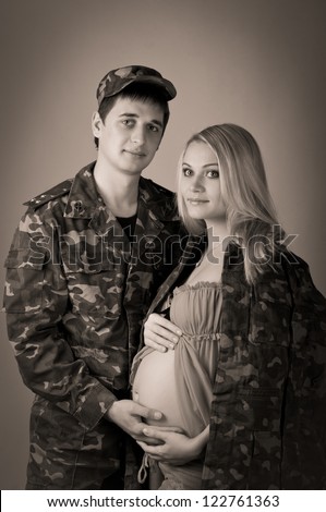 young happy professional soldier man with pregnant woman in black and white