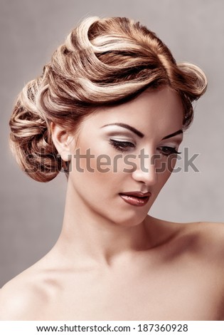 portrait of young woman with makeup and coiffure on grey