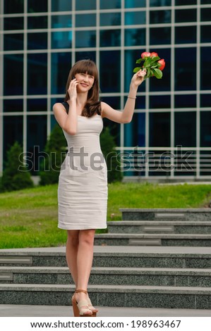 Happy young lady talking on mobile phone with flowers. summer in the city